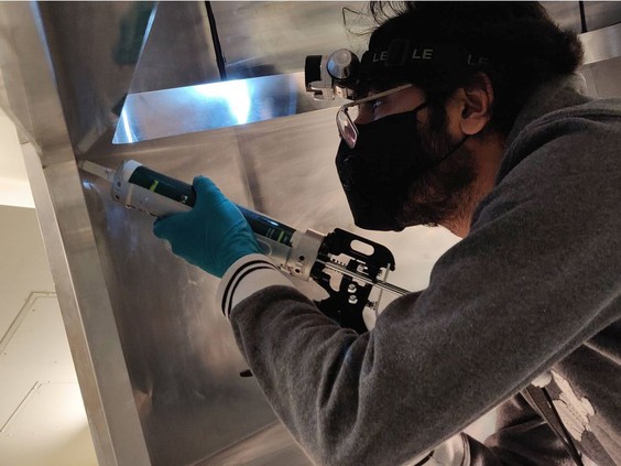 Ali Usman, a PhD student at the University of Regina does some caulking on a prototype of a Cherenkov particle detector in 2021. Photo supplied by Stephen Kay.